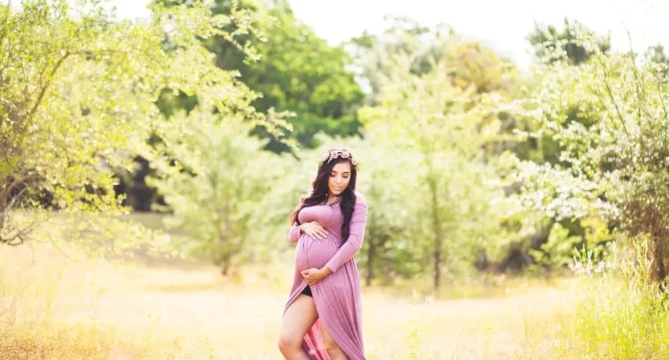 maternity photoshoot of a Woman Standing On Grass Field Surrounded With Trees