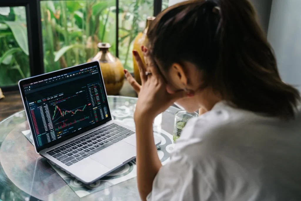 a woman worrying looking at a crypto graph on her laptop screen